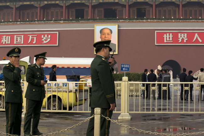 Paramilitary police officers and cleaners work in front of Tiananmen Gate following a car fire in Beijing on Monday.   AP-Yonhap News