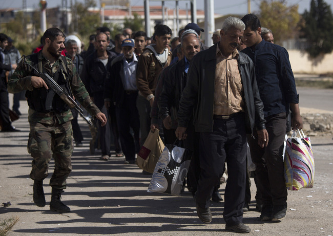 A Syrian soldier escorts men after they arrive from the rebel-held suburb of Moadamiyeh to government-held territory in Damascus on Tuesday.   AP-Yonhap News