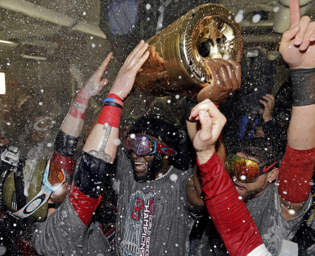 Boston Red Sox's David Ortiz holds up a large bottle of Champagne as he celebrates with teammates after Game 6 of baseball's World Series against the St. Louis Cardinals Thursday in Boston. Ortiz was names the series MVP. (AP-Yonhap News)