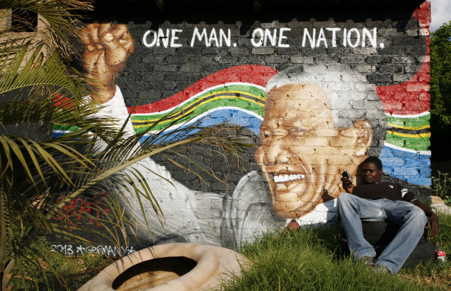 Edmond Hlatswayo sits in front of a wall mural depicting former South African president Nelson Mandela in Johannesburg, South Africa.   AP-Yonhap News
