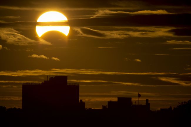 A partial Solar eclipse is seen just after sunrise over the Queens borough of New York across the East River on Sunday in New York. (AFP-Yonhap News)