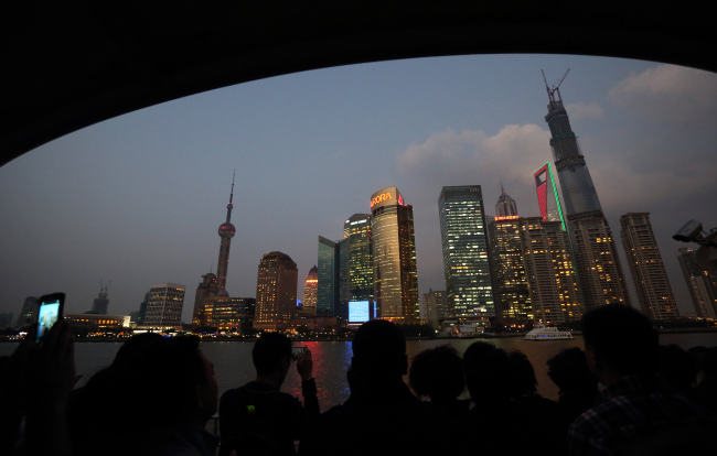Passengers on a ferry look at buildings in the Lujiazui district of Shanghai.   Bloomberg