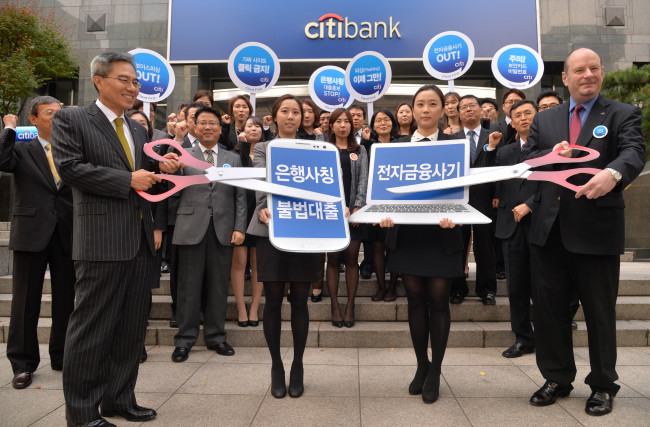 Citibank Korea CEO Ha Yung-ku (left), executives and employees attend a campaign to protect financial consumers from illegal loans and electronic financial scams, held in front of the lender’s headquarters in central Seoul on Monday.  Lee Sang-sub/The Korea Herald