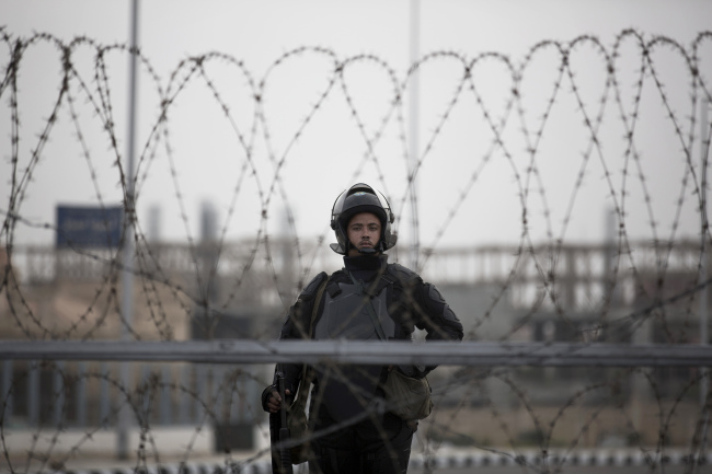 A riot policeman stands guard behind barbed wire outside of a police academy compound where the trial of ousted President Mohammed Morsi was held in Cairo on Monday.   AP-Yonhap News