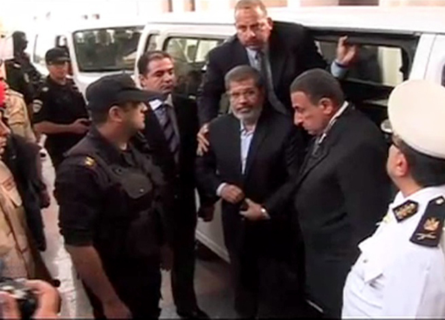 This image made from video provided by Egypt’s Interior Ministry shows ousted President Mohammed Morsi (center) arrives for a trial hearing in Cairo on Monday.   AP-Yonhap News