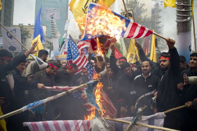 Iranian demonstrators burn American and Israeli flags in front of the former U.S. Embassy building in Tehran on Monday.   UPI-Yonhap News