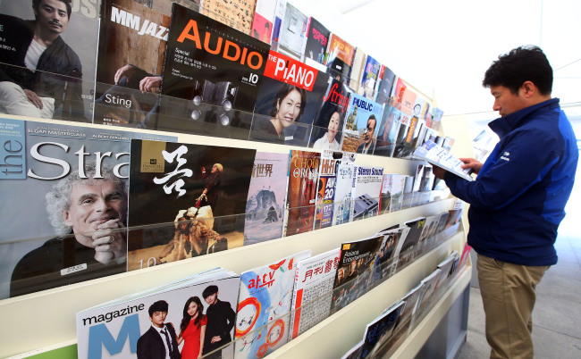 A visitor to the Korea Magazine Festival reads a magazine at Gwanghwamun Square in Seoul on Friday.    Yonhap News
