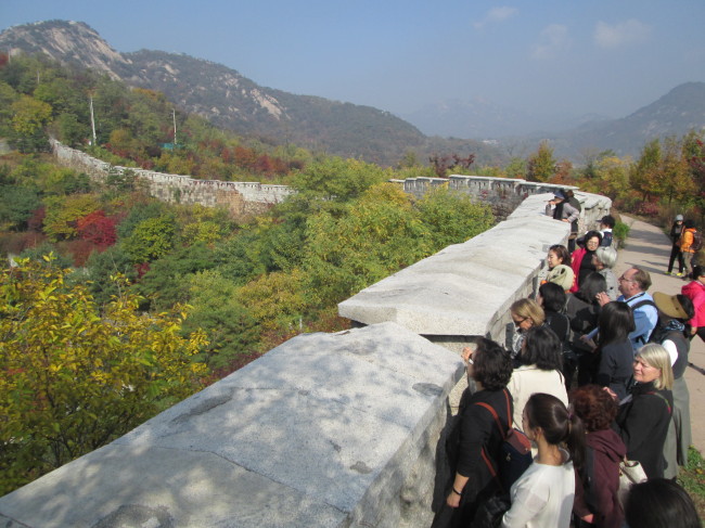 Participants of YEOL Korean Heritage Preservation Society’s English walking lecture on Tuesday look at Mount Inwangsan from Seoul Fortress Wall in Seoul.   Bae Ji-sook/The Korea Herald