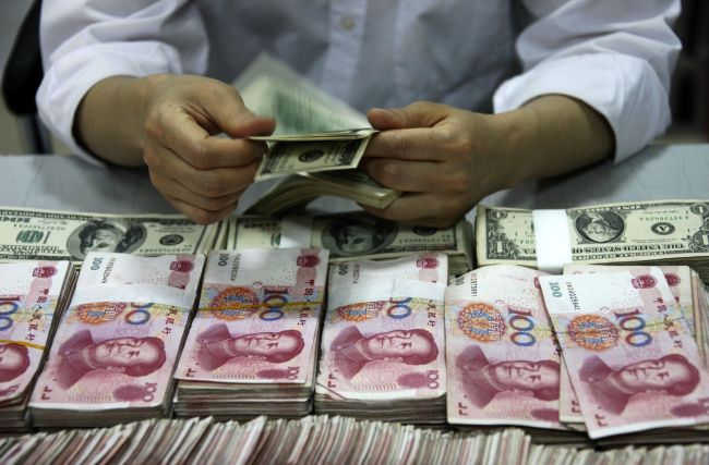 U.S. dollar notes being counted next to stacks of Chinese 100 yuan notes at a bank in Huaibei, China.   AFP-Yonhap News