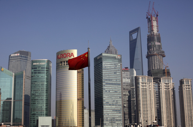 China’s national flag flies in front of commercial buildings in the Pudong area of Shanghai.   Bloomberg
