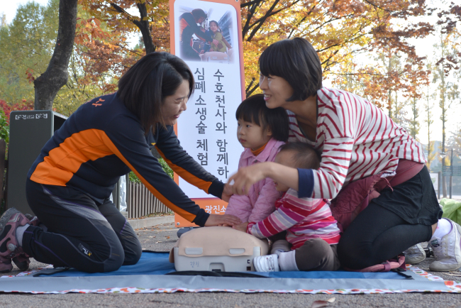 의용소방대원으로 봉사 중인 이인숙(왼쪽) 씨가 아이들과 함께 나온 이웃 주민에게 심폐소생 체험에 대해 설명하고 있다.