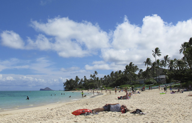 This Oct. 29 photo shows people at Lanikai Beach in Kailua, Hawaii. The Kailua Neighborhood Board is upset about a thriving industry of illegal bed-and-breakfast and vacation rentals and is asking the state tourism agency to stop encouraging visitors to stay overnight in their town.   AP-Yonhap News