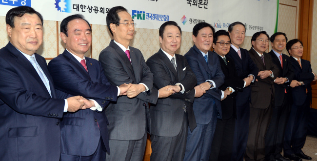 Rep. Choi Kyung-hwan (fifth from left) and Rep. Jun Byung-hun (sixth from left), floor leaders from the ruling and opposition parties, join hands with leaders from the nation’s five business associations before holding a meeting in the National Assembly on Friday.   Park Hyun-koo/The Korea Herald