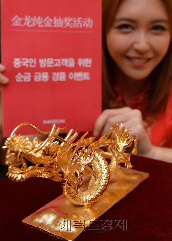 18일 신세계백화점 본점 명품관에서 모델이 중국인 고객을 대상으로 경품을 내건 황금룡 100돈 경품모형을 선보이고 있다. 신세계백화점은 12월 31일까지 물건을 사는 중국인 고객을 대상으로 1명을 추첨해서 순금 103.5돈으로 제작한 용 조각품을 증정할 계획이다.