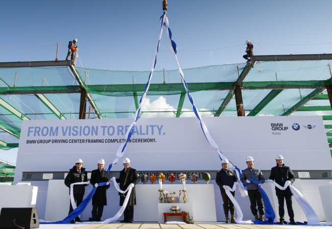 BMW Korea CEO Kim Hyo-joon (third from left) and other company officials celebrate the completion of the frame for a BMW driving center ― first outside of Germany and the U.S. ― during an event at the construction site on Yeongjongdo Island, Incheon, Tuesday.   BMW Korea