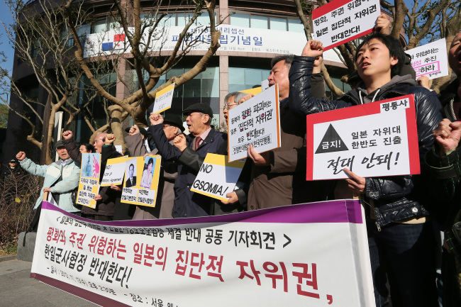 13일 오후 서울 중구 소공동 웨스틴조선호텔 앞에서 열린 '일본의 집단적 자위권 및 한일군사정보보호협정 체결반대 공동기자회견'에서 참가자들이 한일군사협정을 반대하는 구호를 외치고 있다. (연합뉴스)