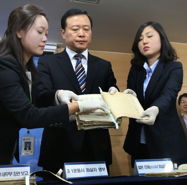 National Archives President Park Kyung-kook (center) holds up the list of Koreans killed after the 1919 independence movement and the 1923 Kanto earthquake at the government complex in Seoul on Tuesday.   Yonhap News