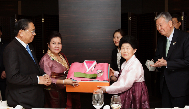 Booyoung Group chairman Lee Joong-keun (right) and his wife Na Gil-soon present hanbok as gifts to Laotian President Choummaly Sayasone and his wife after talking about issues of mutual economic concern at a luncheon in Seoul on Saturday.   Booyoung Group