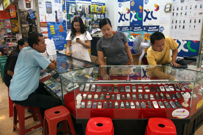 A shopper looks at mobile phones at a shop at Ambassador Mall in Jakarta, Indonesia.   Bloomberg