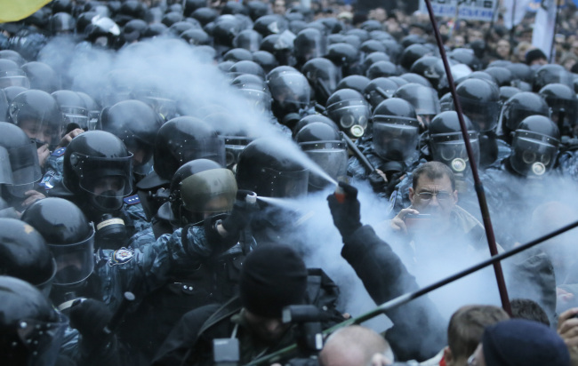 Opposition protesters and riot police spray tear gas against each other in front of the Ukrainian Cabinet of Ministers in Kiev, Ukraine, Sunday.   AP-Yonhap News