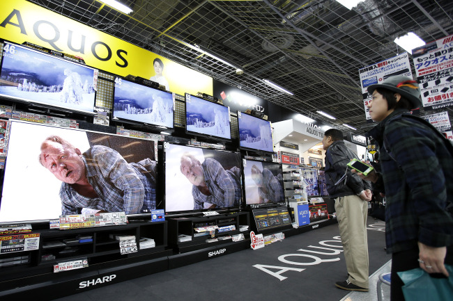 Customers look at Sharp televisions displayed at an electronics store in Tokyo.   Bloobmerg