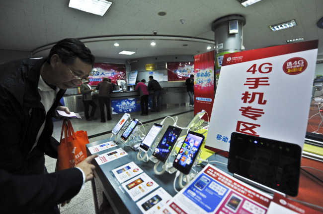 A staff member introduces the service of 4G mobile network to a customer in Beijing, China.   Xinhua-Yonhap News