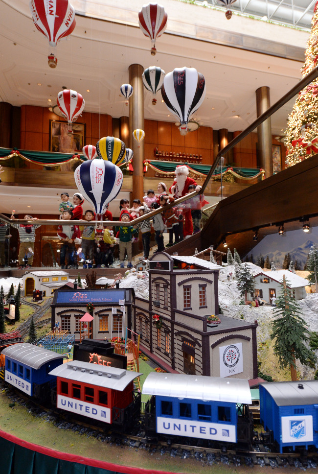 Children and hotel staff dressed in festive holiday attire look at the newly installed Christmas train at the Millennium Seoul Hilton on Wednesday. The annual Christmas train, which has been installed at the hotel for 18 consecutive years, will run until Feb. 2. Donations from more than 60 companies that have sponsored the display have also been collected and sent to social welfare facilities.   Ahn Hoon/The Korea Herald