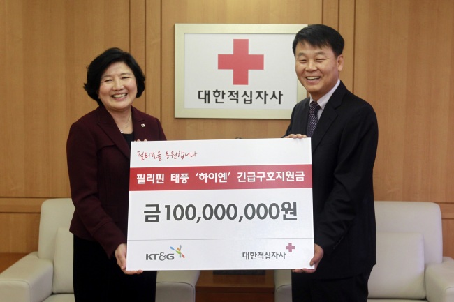Kim Tae-sub (right), managing director and head of KT&G’s sustainability management office, delivers 100 million won ($94,300) from the tobacco and ginseng corporation to Yu Jung-keun, president of the Korean Red Cross, for relief aid to the typhoon-devastated Philippines at the Red Cross in Seoul on Wednesday.   KT&G