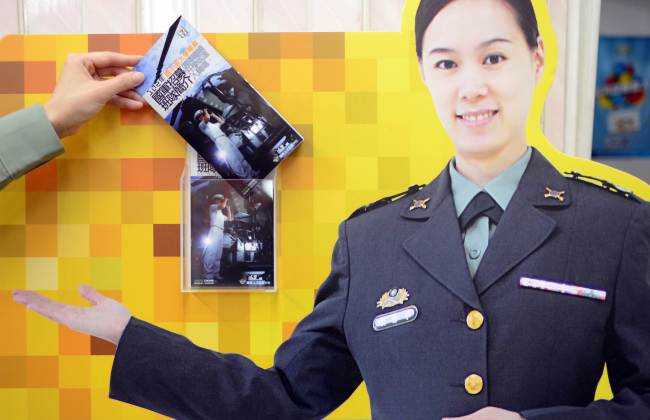 A female sergeant picks up the advertisement at the entrance of a military recruitment center in Taipei.   AFP-Yonhap News