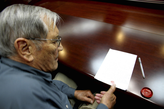 In this Nov. 9 photo released by the Korean Central News Agency and distributed Saturday by the Korea News Service, U.S. citizen Merrill Newman applies his thumb print to a document which North Korean authorities say was an apology that Newman wrote and read out in North Korea.   AP-Yonhap News