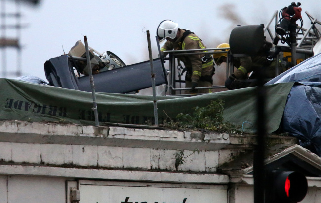 Scottish Fire and Rescue services look at the exposed part of a helicopter tail fin and rotor Saturday, at the scene of a helicopter crash at the Clutha Bar in Glasgow, Scotland.   AP-Yonhap News