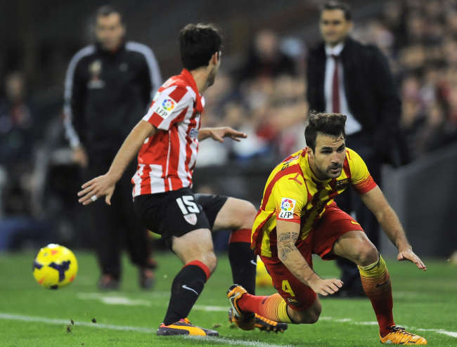 Barcelona’s Francesc Fabregas (right) is tackled by Athletic Bilbao’s Andoni Iraola on Sunday.   AP-Yonhap News