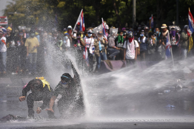 Antigovernment protesters are sprayed water cannon by police in Bangkok on Monday.   AP-Yonhap News