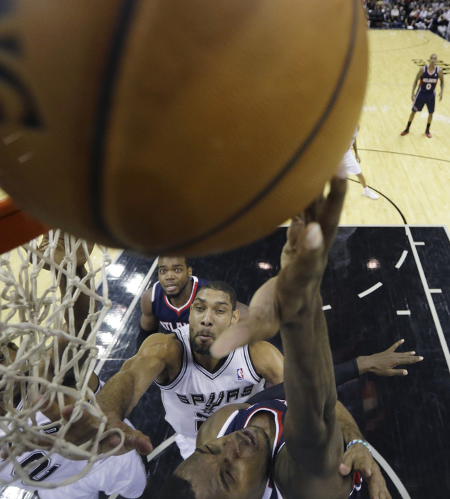 Atlanta Hawks’ Shelvin Mack (right) shoots as San Antonio Spurs’ Tim Duncan (center) defends in San Antonio on Monday.   AP-Yonhap News