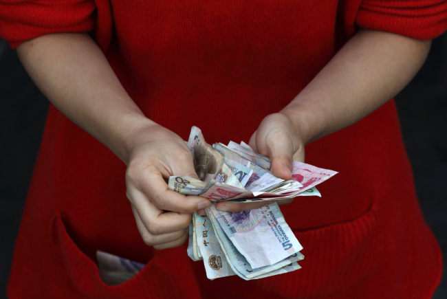 A vendor counts yuan notes at her stall in Wuhan, China.   Bloomberg