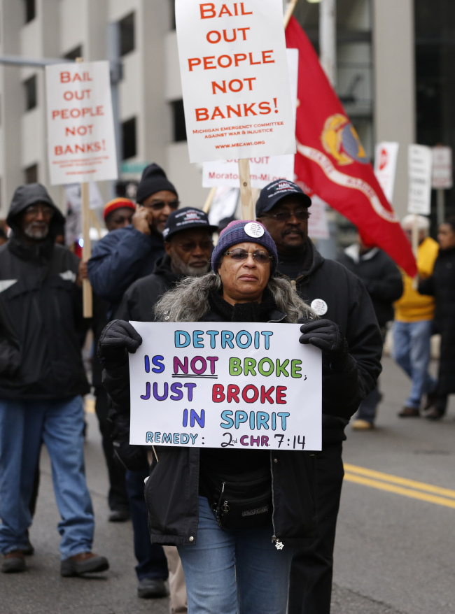 Protesters hold signs as they march outside the Theodore Levin U.S. Courthouse in Detroit, Michigan, Tuesday.   Bloomberg