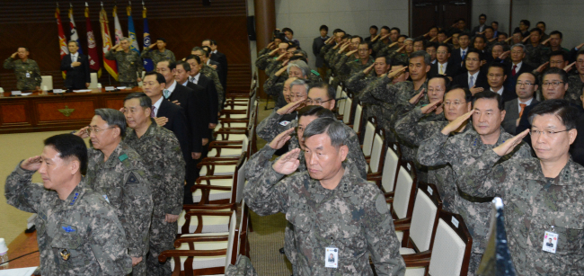 Defense Minister Kim Kwan-jin (second from left, at rear) and top military commanders salute the national flag on Wednesday at the Ministry of Defense ahead of a semiannual commanders’ meeting.   Chung Hee-cho/The Korea Herald.