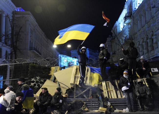 A protester waves a Ukrainian national flag on a barricade during an opposition rally at Independence Square in Kiev on Wednesday.   AP-Yonhap News
