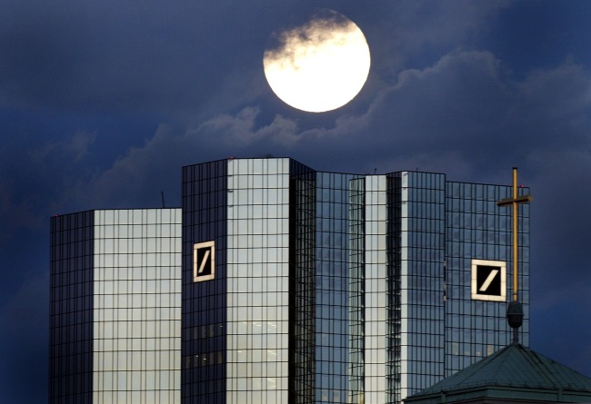 A rising full moon is seen over the twin towers of the Deutsche Bank headquarters in Frankfurt.   Bloomberg