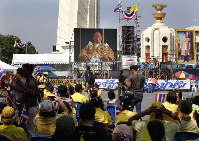 People listen to King Bhumibol Adulyadej speak on a giant screen on his 86th birthday at the Democracy Monument in Bangkok on Thursday.   AP-Yonhap News