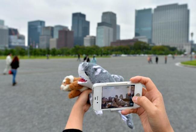 Tour operator Sonoe Azuma takes a picture of stuffed toys during a visit to a tourist area in Tokyo.    AFP