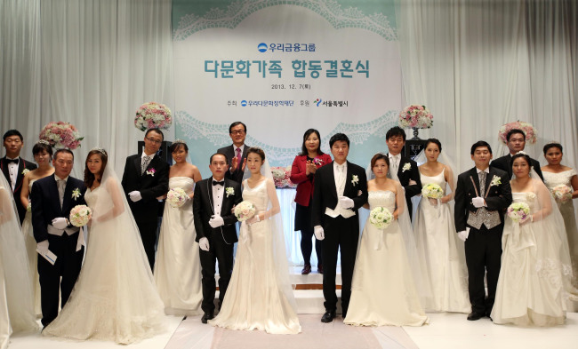 Woori Financial Group chairman Lee Soon-woo (left, back row) applauds after conducting a group wedding of 10 multicultural couples at the group headquarters in central Seoul, Saturday. The event was hosted by the Woori Multicultural Scholarship Foundation and supported by Seoul City for multicultural couples who did not have a wedding ceremony due to economic and other personal reasons.
Woori Financial