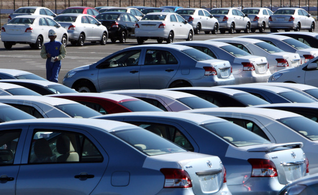 An employee passes Yaris automobiles manufactured by Toyota Motor Corp. and awaiting shipment at the Central Motor Co.’s Miyagi plant in Ohira Village, Miyagi prefecture, Japan.   Bloomberg