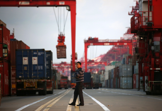A man walks past shipping containers at the Yangshan Deep Water Port in Shanghai.  Bloomberg