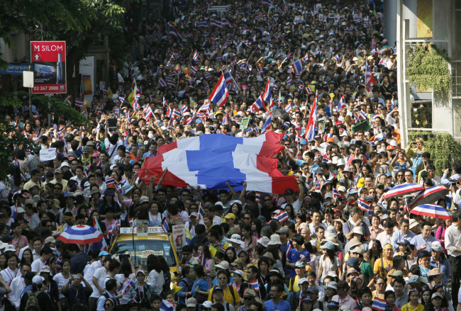Antigovernment protesters carry the Thai national flag as they march in Bangkok on Monday.   AP-Yonhap News