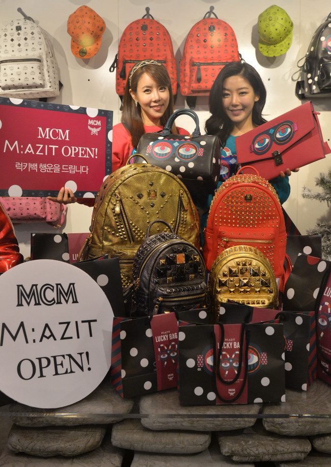 Sales clerks promote a sales event for M:AZIT, a store opened by MCM, a luxury German leather brand, in Seoul on Thursday. To celebrate its opening, the store will sell a dozen randomly selected MCM items originally priced between 600,000 and 2 million won for 120,000 won each day on a first come, first served basis until Jan. 24.   Lee Sang-sub/The Korea Herald