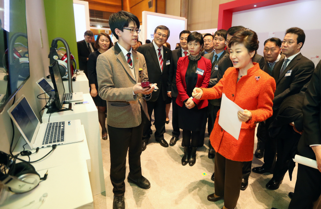 President Park Geun-hye looks at a remote control for a speaker system developed by a high school student at Creative Korea 2013 at the Coex mall, Seoul, Thursday.    Yonhap News
