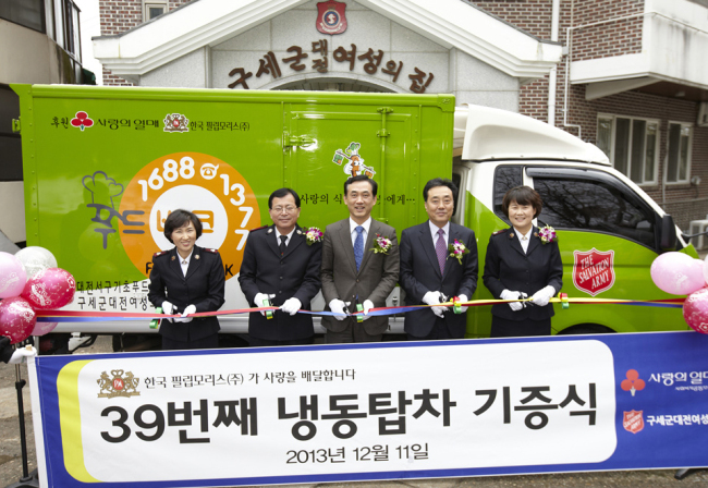 Philip Morris International Korea donated a freezer truck to a women and children’s welfare center run by the Salvation Army Korea Territory in Daejeon on Wednesday. The 39th freezer truck donated by the company will be used by the center to deliver foods to neighbors in need. Kim Brian (center), director of Philip Morris International Korea, cuts the tape at the donation ceremony.   Yonhap News