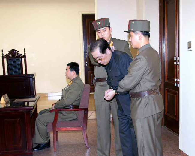 A photograph from North Korea’s Rodong Sinmun shows Jang Song-thaek (center) in handcuffs as he is escorted by military officers to his trial on Thursday.   Yonhap News