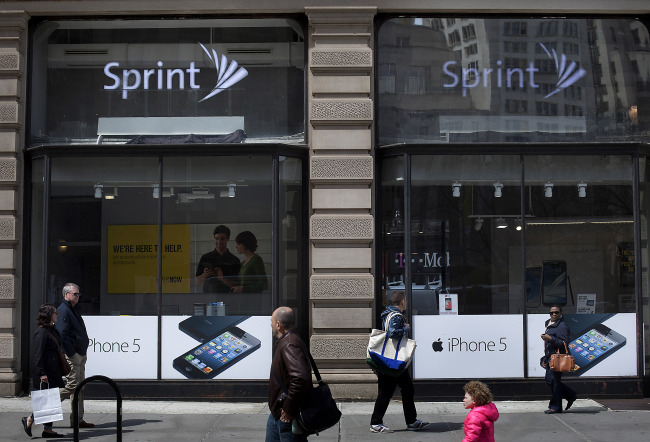 Pedestrians pass in front of a Sprint Nextel Corp. store in New York.   Bloomberg